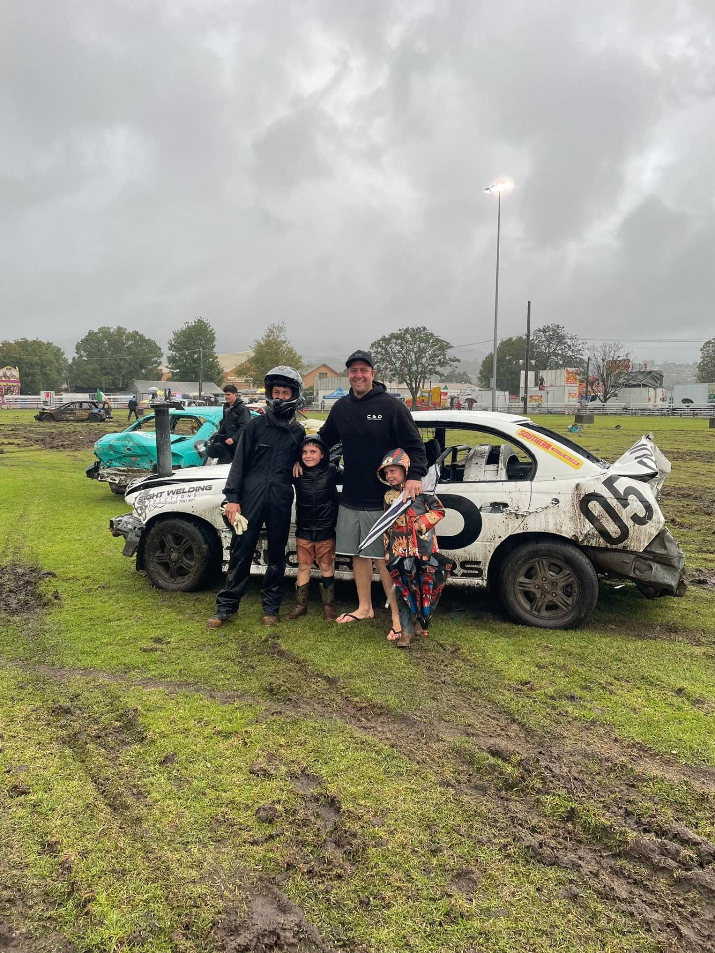The C and D Truck Repairs crew and family beside their demolition derby car